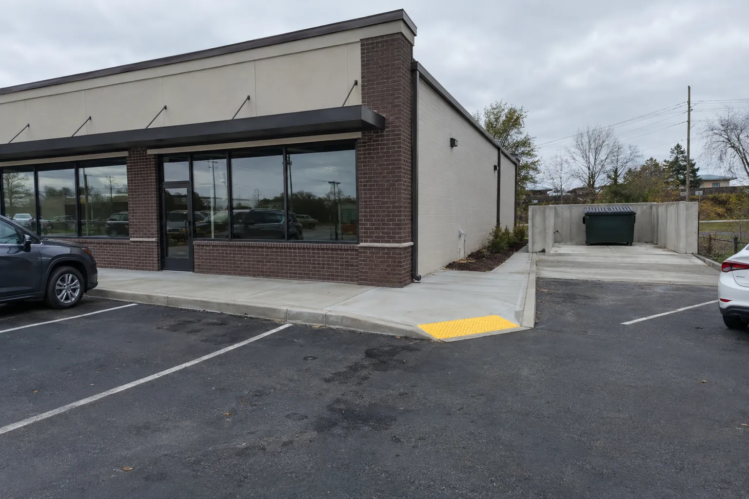 New commercial concrete sidewalk, curb ramp, and dumpster pad at a retail building in Clarksville, TN